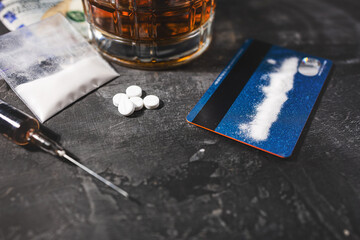 White narcotic pills, an alcoholic drink in a glass, a syringe with a dose of heroin, a line of...