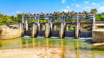 Dam on a River: A concrete dam stands guard across a tranquil river, its spillway cascading water...