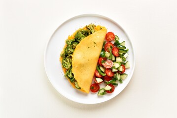 Omelet with roasted broccoli and cheese served with salad from fresh vegetables