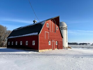 A wonderfully kept up old wood red livestock barn on a snow fall landscape