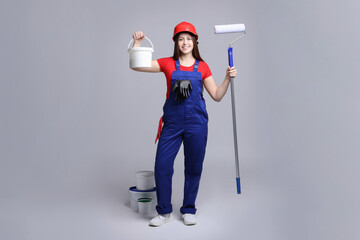 Professional painter with roller and buckets of paint on light grey background