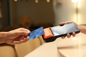 Man paying with credit card via terminal in cafe, closeup