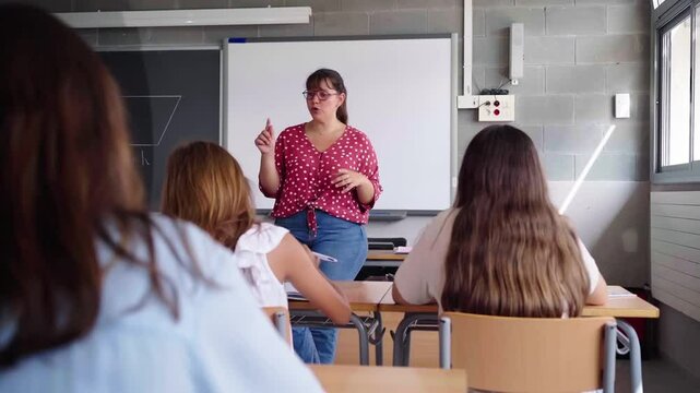 Female professor teaching in front of elementary school students in a classroom. Video with copy space.