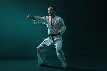 Man wearing uniform practicing karate in color lights