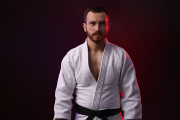 Karate fighter wearing uniform in color light against black background