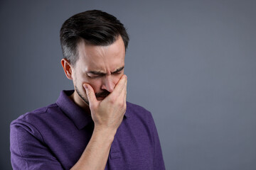 Sad man crying on grey background, space for text