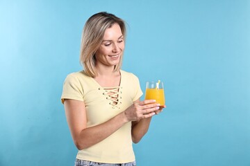 Woman with glass of orange juice on light blue background. Refreshing drink