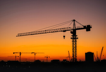 Large crane silhouette against sunset at construction site, Labor Day
