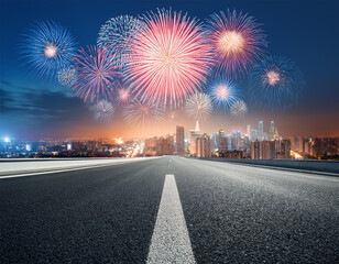 fireworks display over a city skyline with an empty road leading into the distance