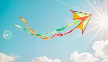 Colorful kite soaring in clear blue sky with soft clouds, freedom