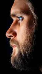 Obraz premium Bearded man stares pensively into the distance in a dark studio. Headshot closeup