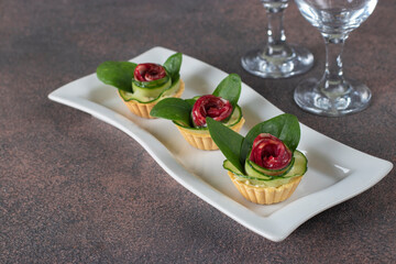 Tartlets in shape of roses with sausage, cucumber, cheese and spinach, festive snack
