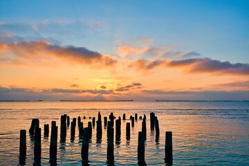 Obraz premium Evening seascape. Piles of the old sea pier in the water. Selective focus.