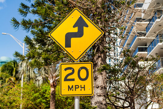 Road sign of speed limit 20 mph. Caution yellow road sign. Traffic sign on the road. Attention caution road sign. Speed limit 20 mph. Direction route sharp turn