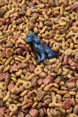 Black plastic dog sitting on colorful dry dog food