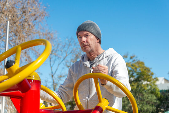man using an outdoor gym using spinning wheel, Tai Chi exercise.