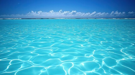 Turquoise ocean surface, calm water, bright sky, idyllic beach scene