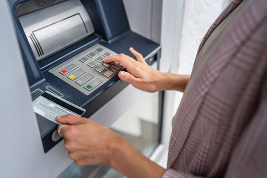 hands of woman using credit card and withdrawing cash at the ATM