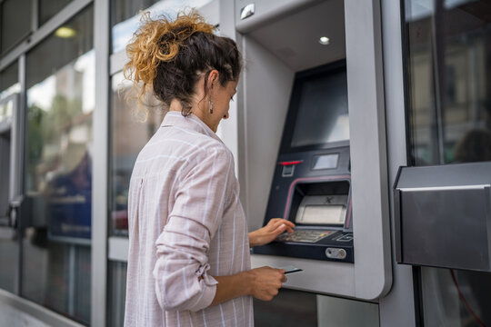 woman using credit card and withdrawing cash at the ATM