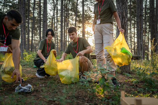 teenage friends young men women pick up waste garbage to clean forest