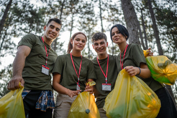 portrait of group of friends volunteers prepare to collect garbage waste and clean forest nature in...