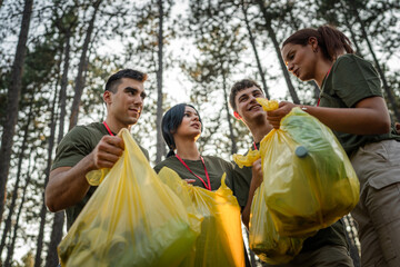 teenage friends young men women pick up waste garbage to clean forest