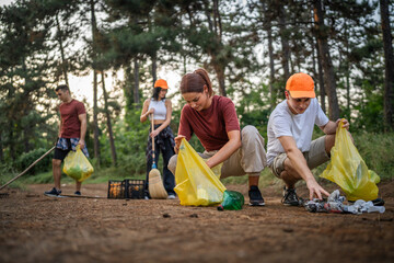 teenage friends young men women pick up waste garbage to clean forest