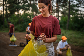 Portrait of caucasian female teenager activist volunteer during picking up waste garbage plastic...