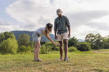 Young couple spraying tick repellent on her legs and arms during a summer nature trip