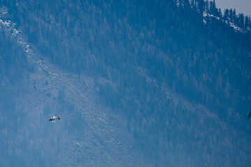 Ein Hubschrauber fliegt vor einem bewaldeten Berghang © Joachim