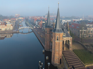 Drone aerial of historic Sneek Waterpoort, water gate tower and tower in soft warm morning light