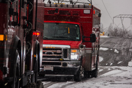 Fire engine and ambulance responding to emergency in falling snow
