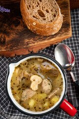 Sour rye soup with pieces of white sausage and mushrooms.