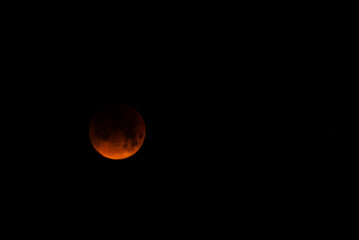 A glowing blood moon during a partial lunar eclipse at night.
