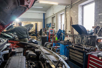 Auto repair shop with tools, auto parts and mechanics working on vehicles.
