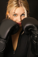 Girl isolated on black background in black clothes in boxing gloves. Woman doing sports. Boxing equipment. Woman and boxing.