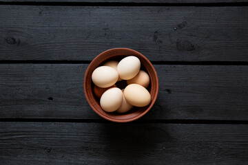Brown chicken eggs in a clay bowl on a wooden table