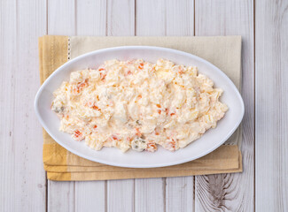 Russian salad or mayonnaise salad in a plate over wooden table