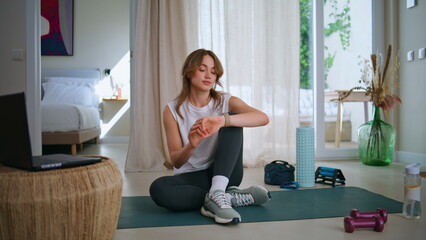 Athletic woman checking smartwatch at home workout session. Relaxed sportswoman