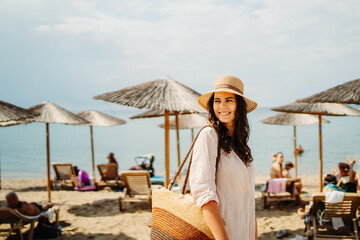 Young caucasian woman is going to the beach with straw bag	
