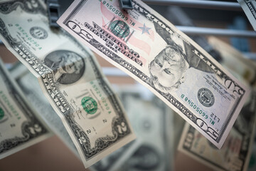 Close-up of U.S. dollar bills hanging on a clothesline, symbolizing money laundering, financial crime, and corruption.