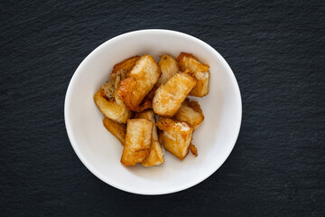 Small pieces of fried chicken breast served in a cup against a black background.
