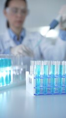 Test tubes with a blue liquid, close-up view. Scientist holding pipette conducting experiments in...