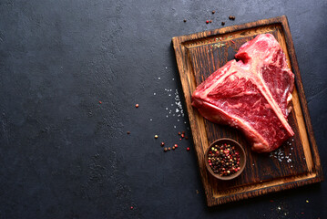 Raw organic T-bone steak with spices . Top view with copy space.