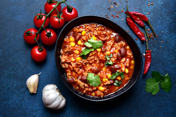 Chili con carne - traditional mexican minced meat and vegetables stew in tomato sauce in a cast iron pan. Top view with copy space.