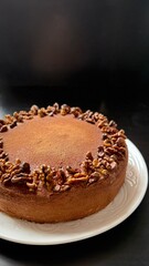 Chocolate cake decorated with walnut on white plate, black background