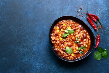 Chili con carne - traditional mexican minced meat and vegetables stew in tomato sauce in a cast iron pan. Top view with copy space.