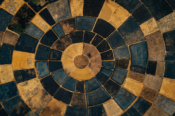 Fototapeta premium A circular pattern of blue and yellow tiles on a sidewalk