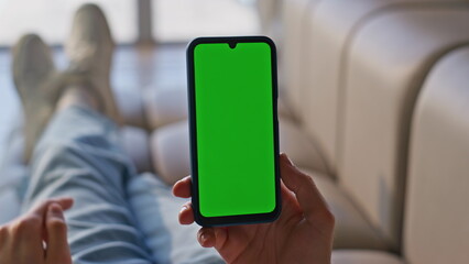 User finger scrolling greenscreen smartphone lying couch closeup. Man swiping
