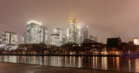 Modern cityscape with illuminated skyscrapers, bridge, and river at night
